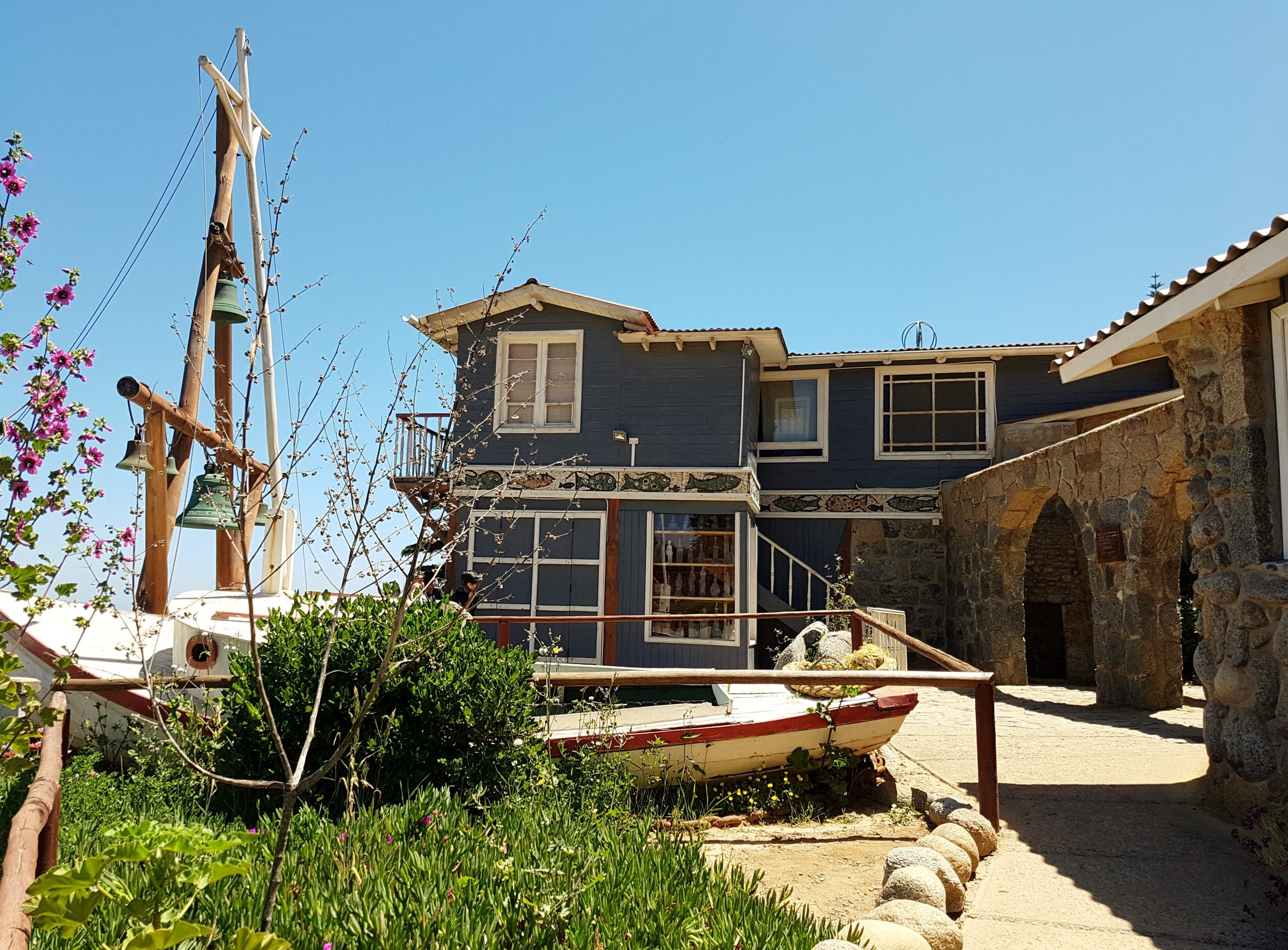 Casa-museo de Neruda en Isla Negra: madera azul sobre piedra, con mástil y barca